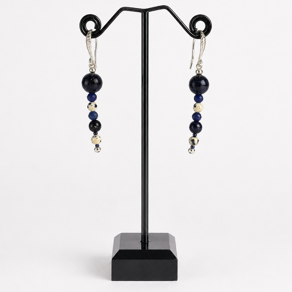 A pair of beaded drop earrings displayed on a black jewelry stand against a light gray background. The earrings feature dark navy blue and black round beads, small metallic silver beads, and silver hook ear wires.